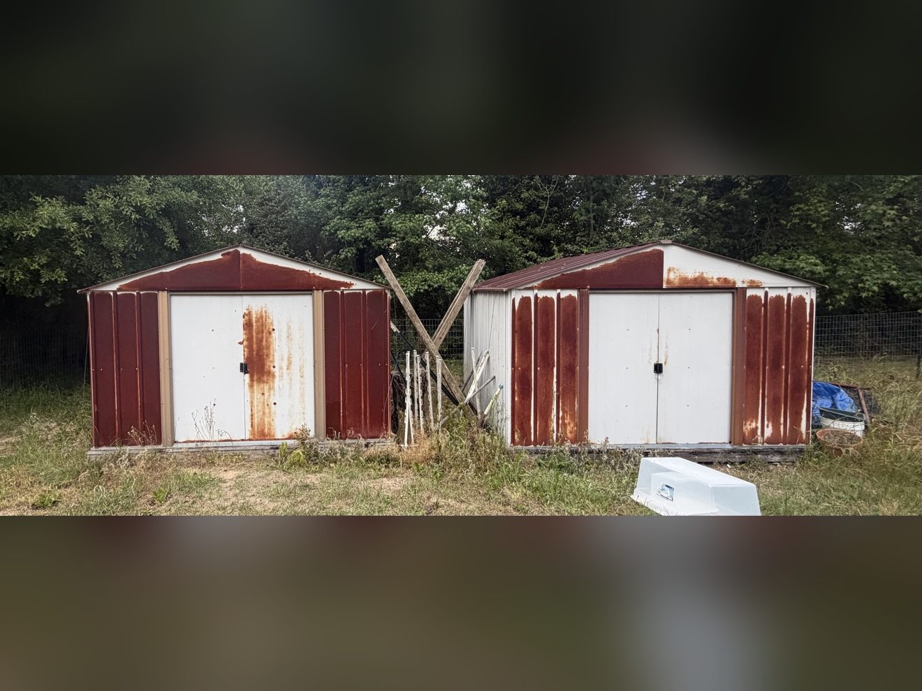 Weathered sheds with rust streaks before repainting